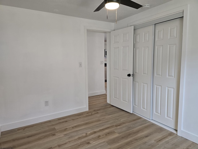 unfurnished bedroom with light wood finished floors, a closet, a ceiling fan, and baseboards