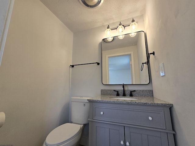 half bath with toilet, a textured ceiling, vanity, and visible vents