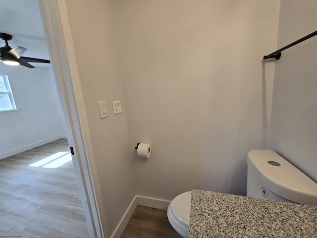 bathroom featuring toilet, ceiling fan, baseboards, and wood finished floors