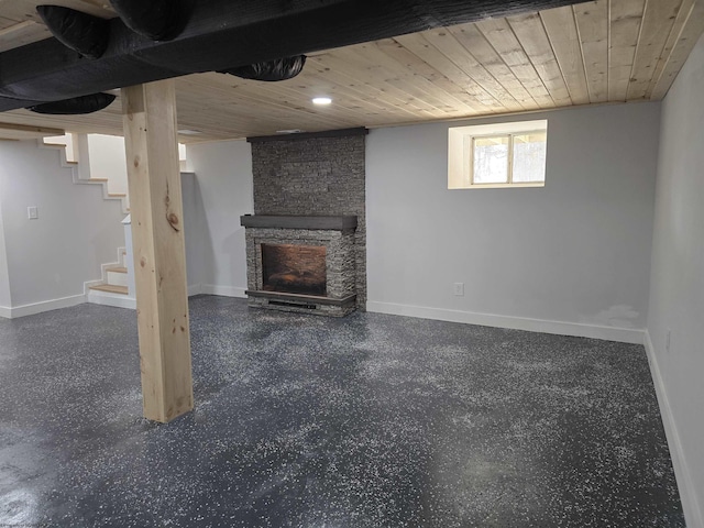 basement featuring a stone fireplace, wooden ceiling, and baseboards