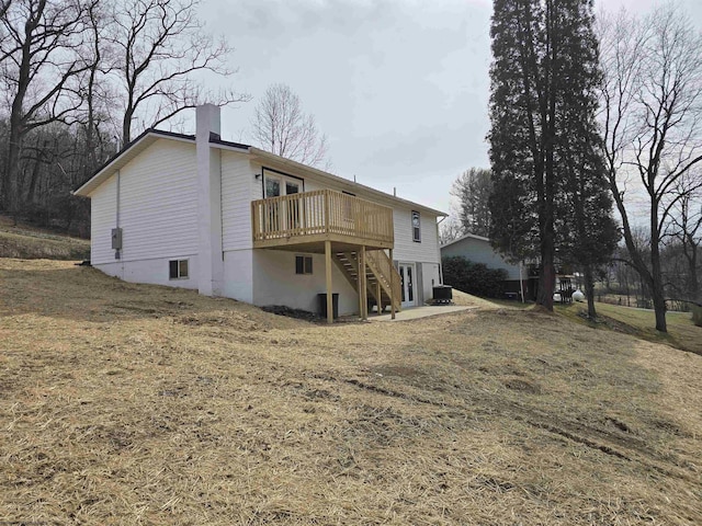 back of house with a chimney, a wooden deck, and stairs