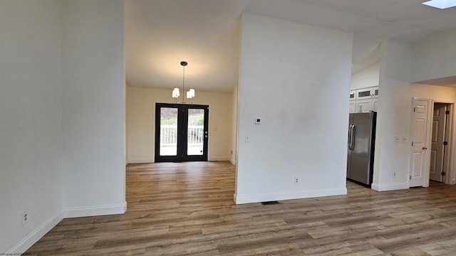 entrance foyer featuring a chandelier, high vaulted ceiling, wood finished floors, baseboards, and french doors