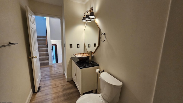 bathroom featuring toilet, baseboards, wood finished floors, and vanity