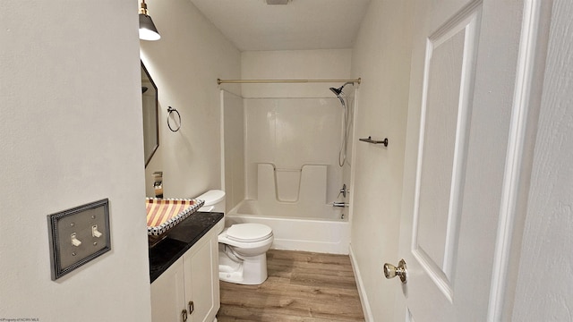 bathroom with baseboards, toilet, wood finished floors, vanity, and shower / washtub combination