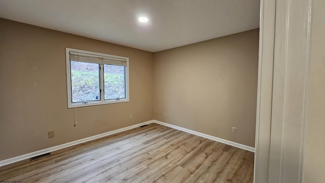 spare room with light wood finished floors, visible vents, and baseboards