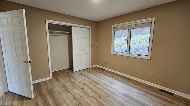 unfurnished bedroom with a closet, light wood-type flooring, visible vents, and baseboards