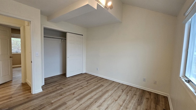 unfurnished bedroom with a closet, wood finished floors, and baseboards