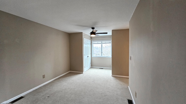 unfurnished room featuring visible vents, a ceiling fan, carpet flooring, a textured ceiling, and baseboards