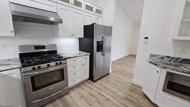 kitchen featuring stainless steel appliances, white cabinetry, and wall chimney range hood