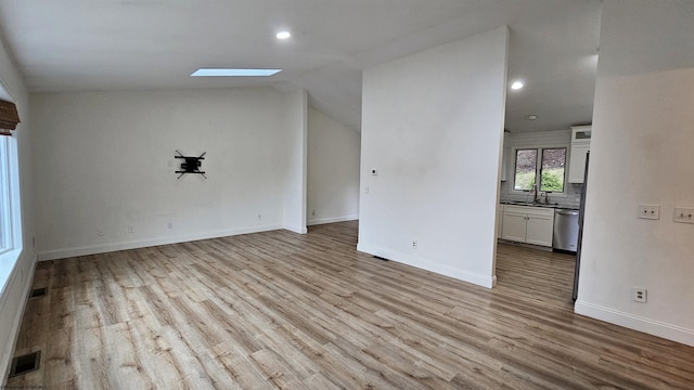 spare room with lofted ceiling with skylight, baseboards, visible vents, and wood finished floors