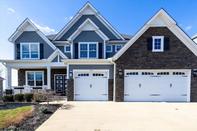 craftsman house with stone siding, concrete driveway, covered porch, and an attached garage