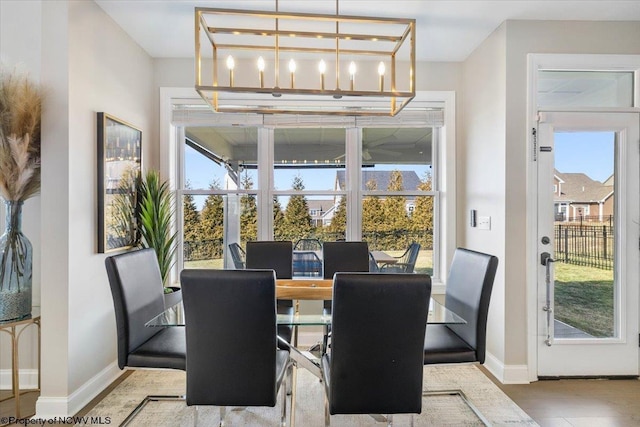 dining room with a notable chandelier, plenty of natural light, and baseboards