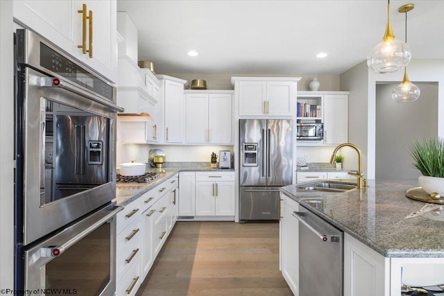 kitchen featuring appliances with stainless steel finishes, a sink, white cabinetry, and light wood-style floors