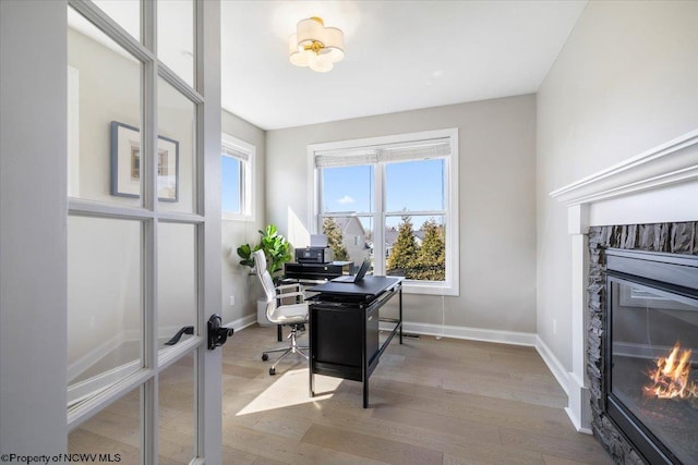 office area with baseboards, french doors, wood finished floors, and a glass covered fireplace