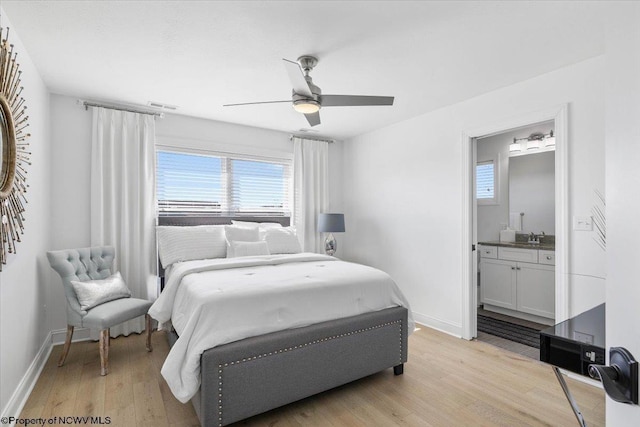 bedroom featuring light wood-type flooring, baseboards, visible vents, and a sink