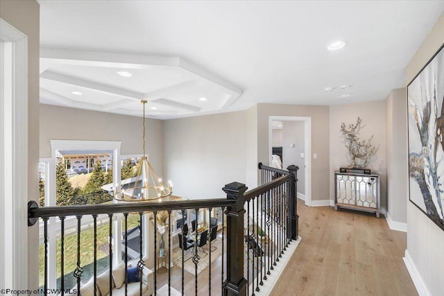 hall with an upstairs landing, a chandelier, light wood-type flooring, coffered ceiling, and baseboards