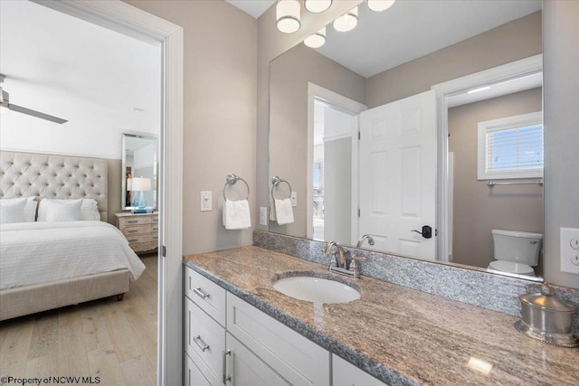 bathroom with toilet, a ceiling fan, vanity, ensuite bath, and wood finished floors