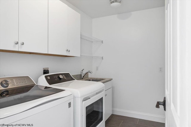 laundry area featuring dark tile patterned floors, a sink, baseboards, washer and dryer, and cabinet space