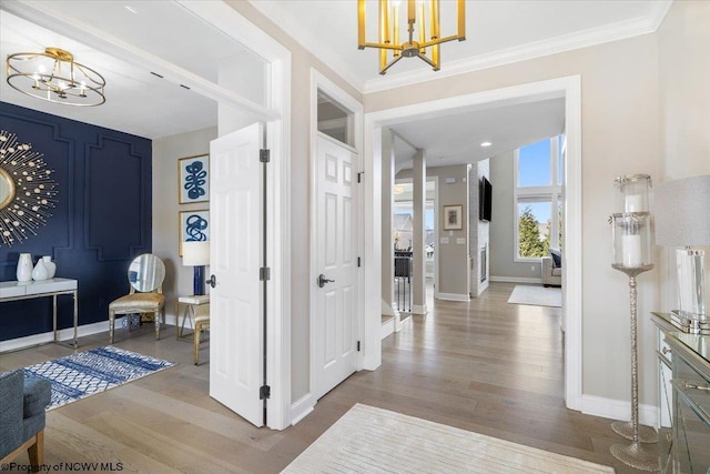 foyer entrance featuring baseboards, crown molding, a chandelier, and wood finished floors