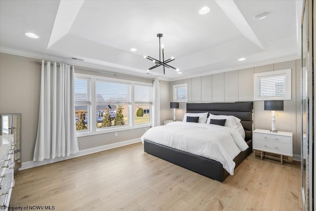 bedroom featuring crown molding, a raised ceiling, visible vents, light wood-style flooring, and baseboards