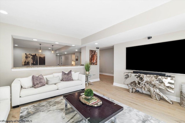 living area with baseboards, light wood-type flooring, and recessed lighting