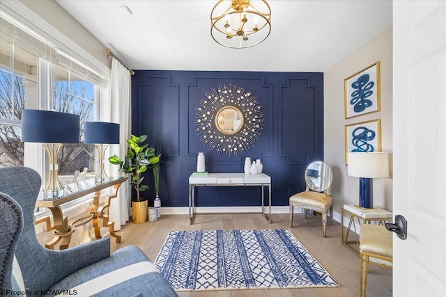 living area featuring baseboards, wood finished floors, and a notable chandelier