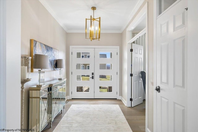 entrance foyer featuring french doors, crown molding, wood finished floors, a chandelier, and baseboards