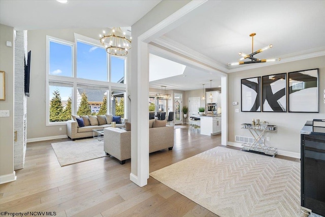 living room with ornamental molding, light wood-type flooring, and a notable chandelier