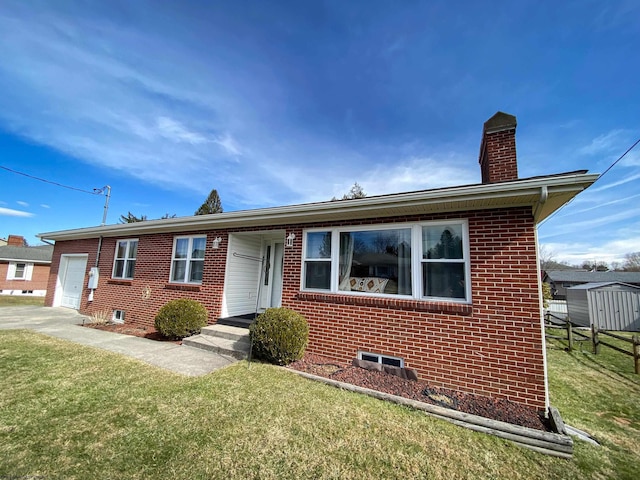 view of front of house featuring a chimney, a front lawn, and brick siding