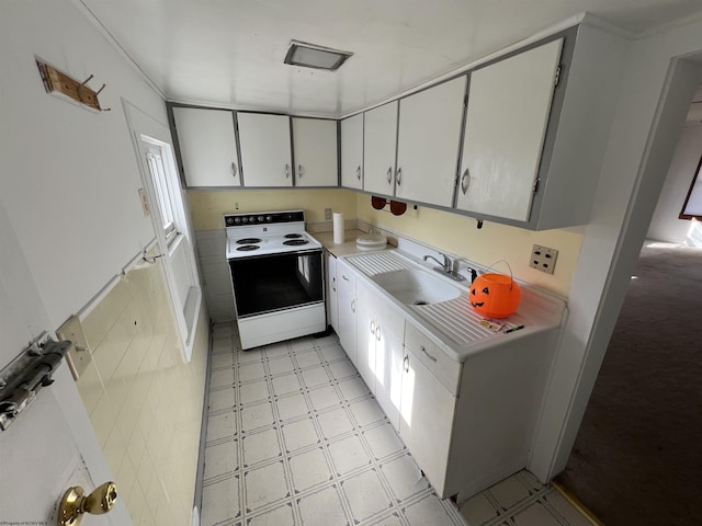 kitchen featuring range with electric stovetop, light floors, light countertops, white cabinetry, and a sink