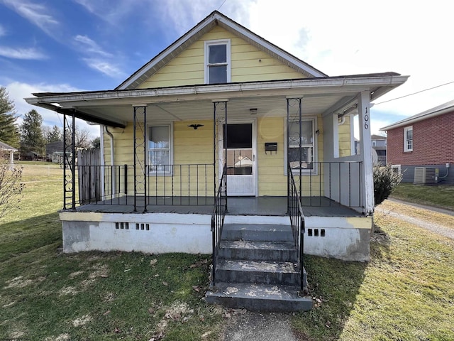 bungalow-style home with a porch, a front yard, crawl space, and cooling unit