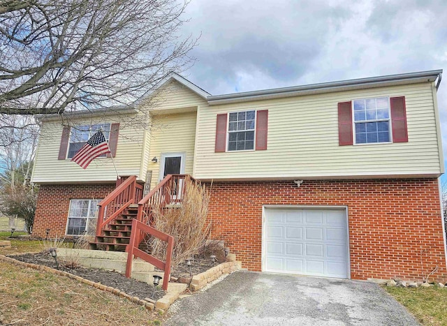 bi-level home with an attached garage, aphalt driveway, and brick siding