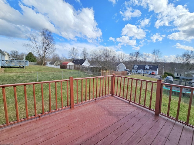 wooden terrace with a fenced backyard, a residential view, a yard, a storage unit, and an outdoor structure