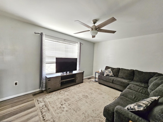 living room featuring visible vents, wood finished floors, a ceiling fan, and baseboards