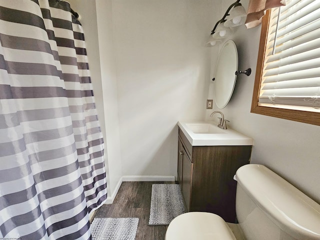 bathroom with wood finished floors, vanity, toilet, and baseboards