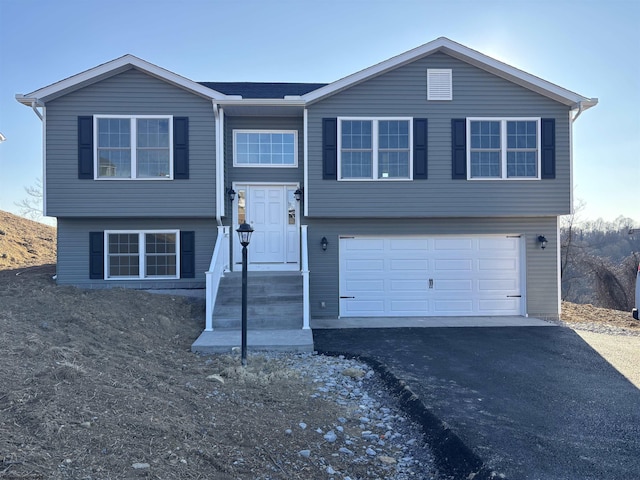 bi-level home featuring a garage and aphalt driveway