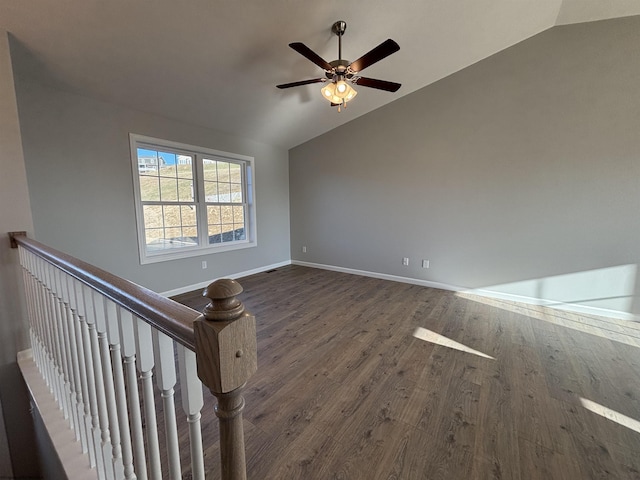 spare room with ceiling fan, vaulted ceiling, baseboards, and wood finished floors