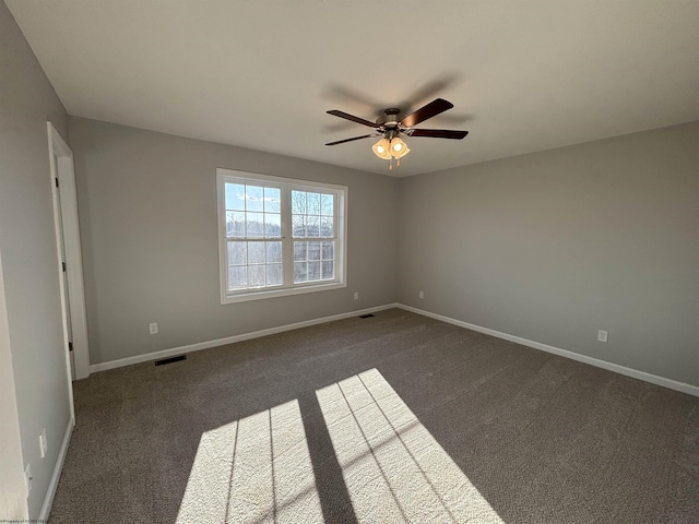 empty room featuring baseboards, visible vents, and dark carpet