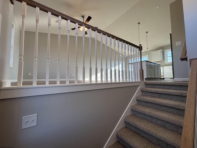 staircase featuring a ceiling fan and baseboards