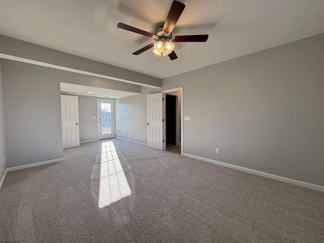 carpeted spare room featuring ceiling fan and baseboards