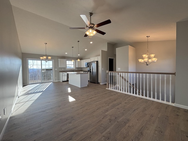 unfurnished living room with baseboards, dark wood-style floors, vaulted ceiling, a sink, and ceiling fan with notable chandelier