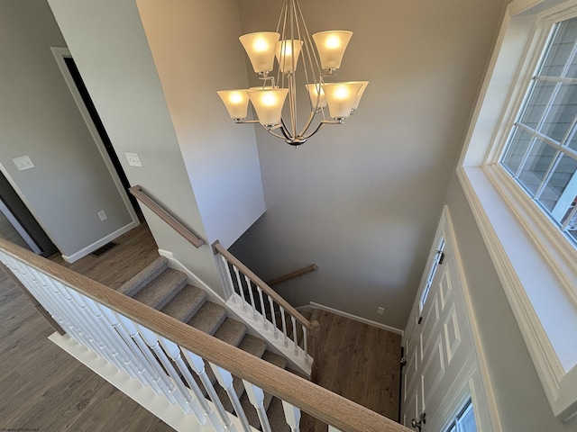 stairs featuring baseboards, wood finished floors, visible vents, and an inviting chandelier