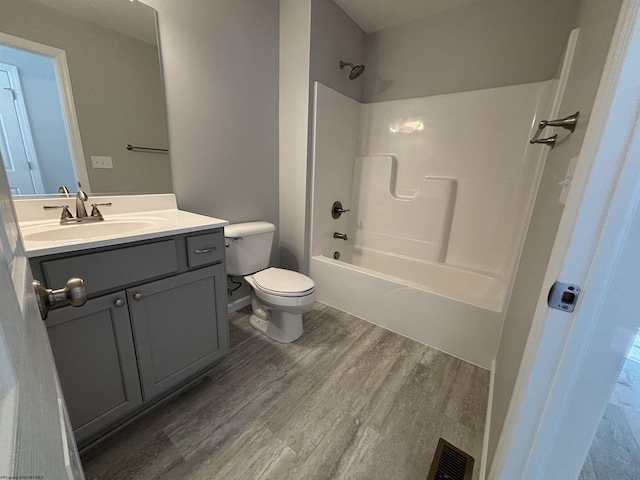 full bathroom with visible vents, toilet, wood finished floors, vanity, and washtub / shower combination