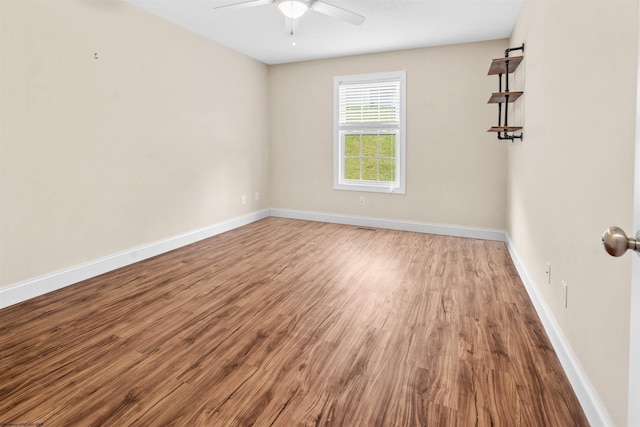 empty room featuring ceiling fan, wood finished floors, visible vents, and baseboards