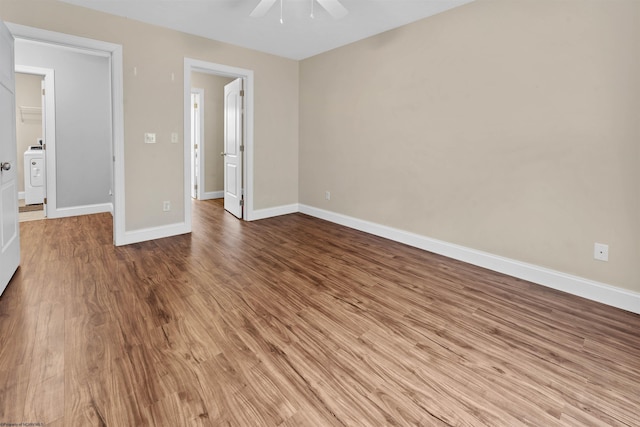 unfurnished bedroom with washer / clothes dryer, wood finished floors, a ceiling fan, and baseboards