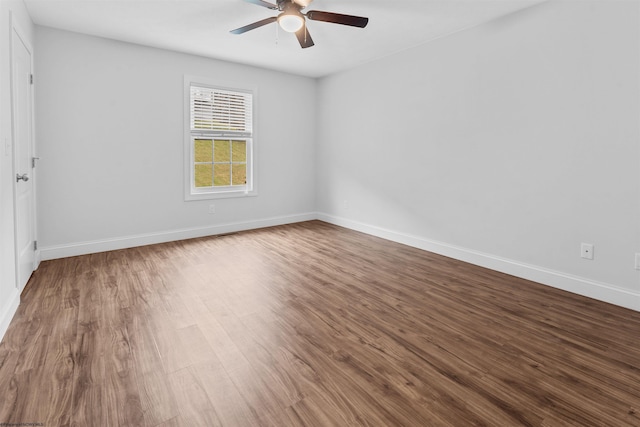 unfurnished room featuring dark wood-style floors, a ceiling fan, and baseboards