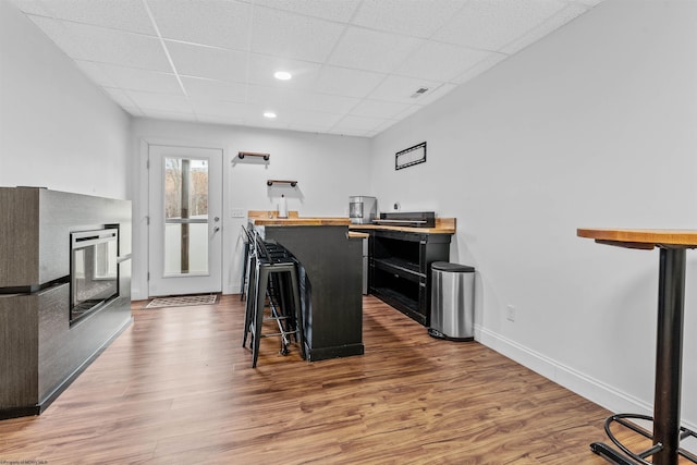 kitchen featuring baseboards, wood finished floors, a kitchen bar, and dark cabinets