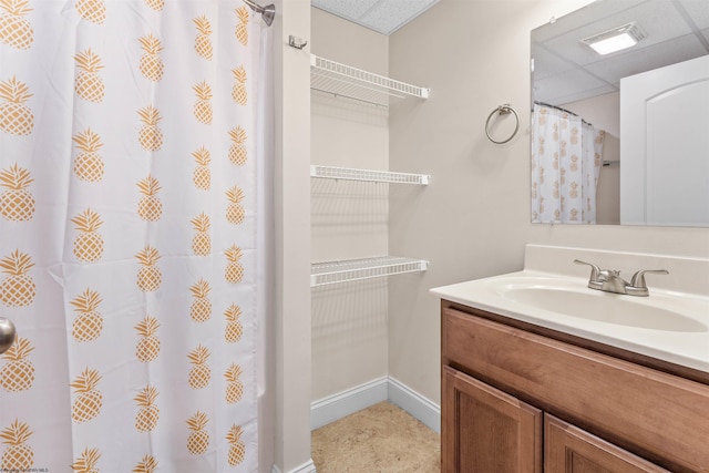 bathroom featuring a paneled ceiling, baseboards, a shower with shower curtain, and vanity