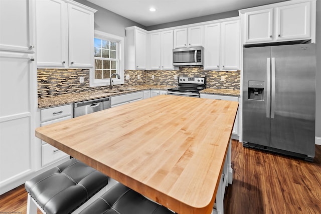 kitchen featuring white cabinets, appliances with stainless steel finishes, dark wood-type flooring, wooden counters, and a sink