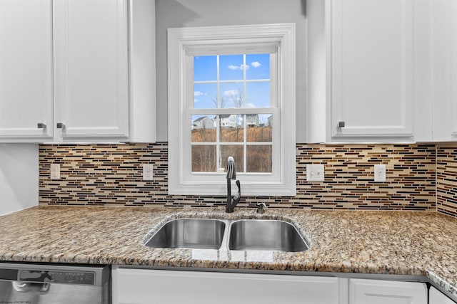 kitchen featuring dishwasher, tasteful backsplash, a sink, and white cabinetry